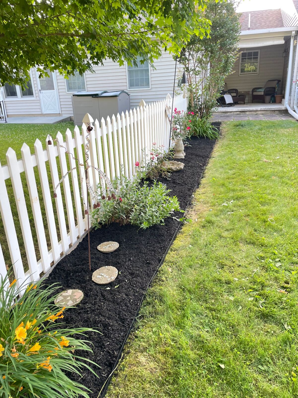 Picket fence flower bed refreshed with dark mulch