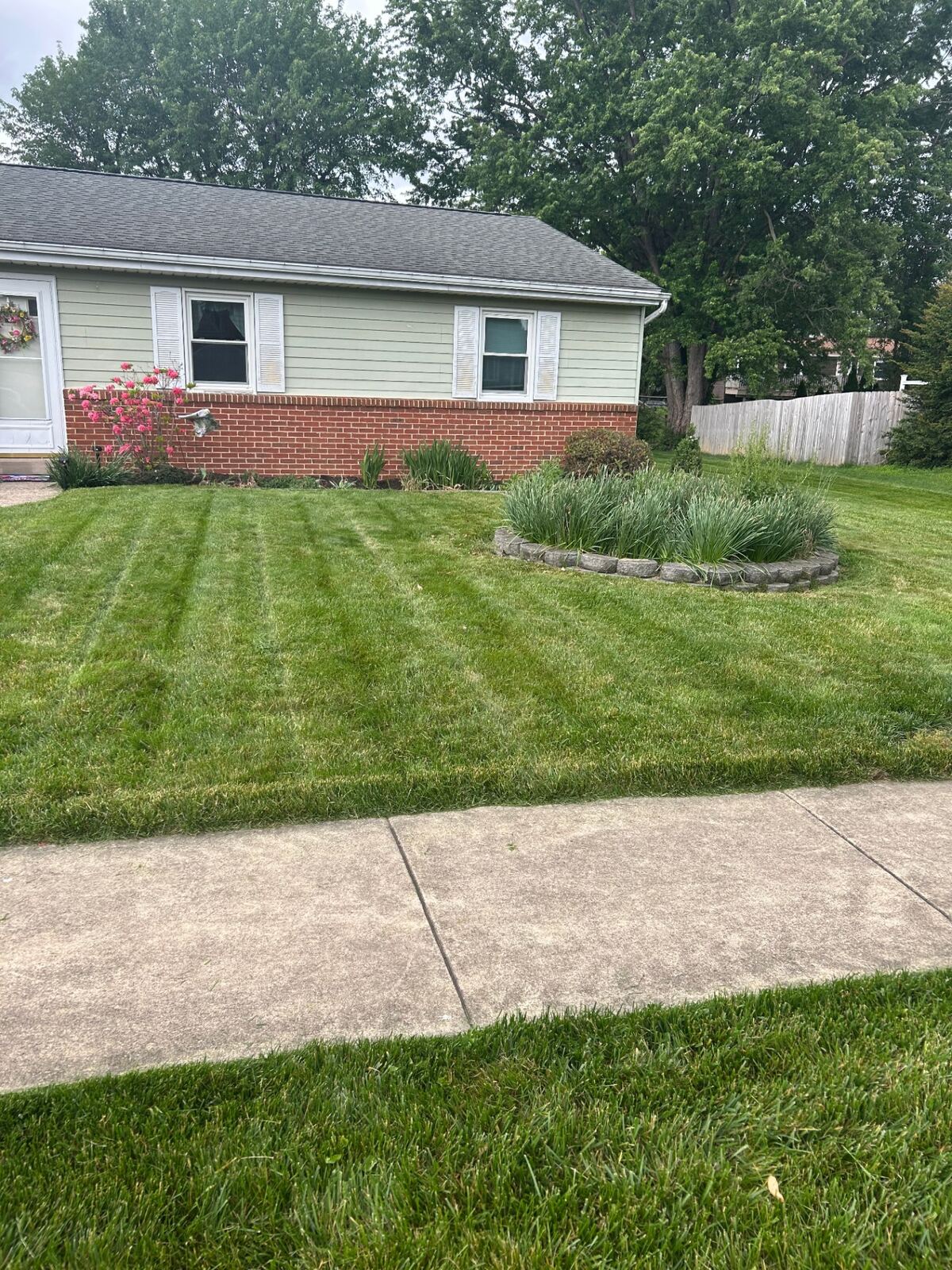 Striped lawn mowing with fresh edging by brick home